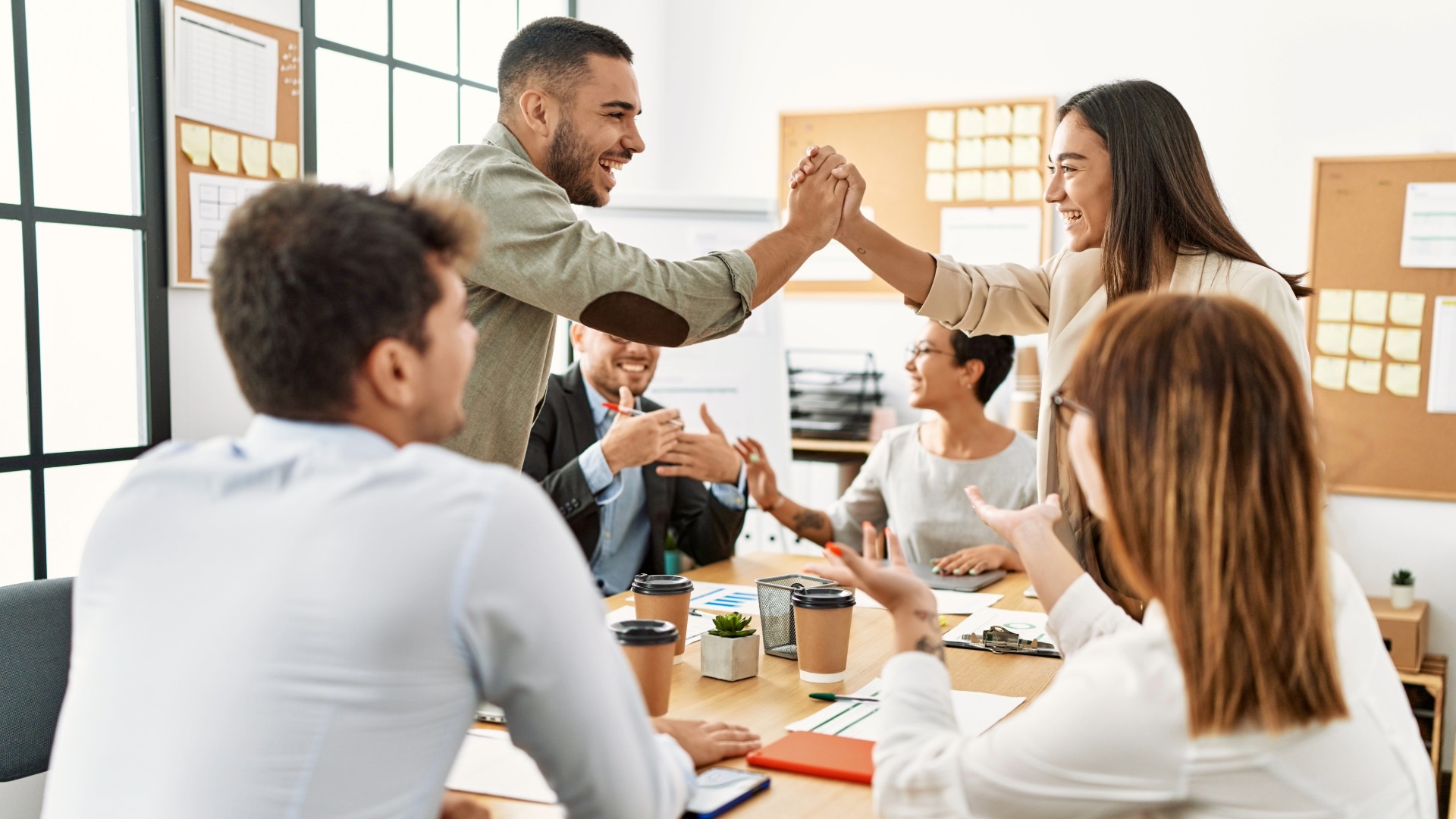 Persone in ufficio, due di queste battono il cinque con la mano Sorridendo