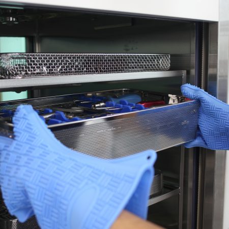 mani che afferrano kit di ferri da un'autoclave