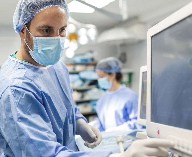 Chirurgo in sala operatoria controlla informazioni sul display di un macchinario.